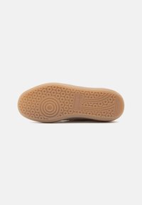 Suola della scarpa realizzata in un materiale gommoso traslucido di colore marrone chiaro, caratterizzata da un design della suola circolare e a motivo per garantire aderenza.