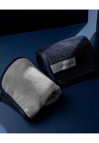 Ręczniki w kolorze granatowym i szarym z teksturowaną powierzchnią, z srebrną etykietą z napisem "ARISTOCRAT." Zrolowane i położone na ciemnoniebieskim tle.