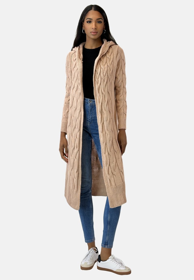 Lång, rosa stickad kofta med flätmönster, öppen fram, huva och ribbade muddar, bärs över en svart topp och blå jeans.