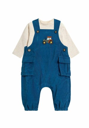 Blå corduroy overalls med to sidelommer, prydet med et traktordesign på brystet, parret med en lys beige langærmet skjorte derunder.