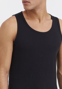 Zwart tanktop van katoen, met een klassieke ronde hals en mouwloos ontwerp. Strakke textuur en aansluitende pasvorm.