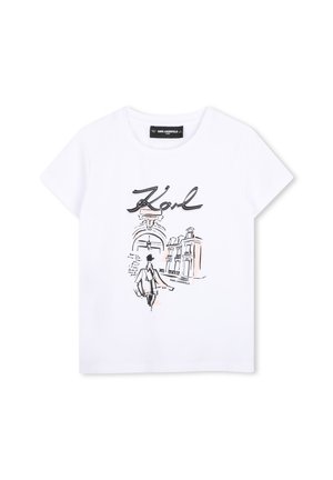 T-shirt blanc à manches courtes avec un croquis noir d'une personne, de bâtiments et le texte "Karl" en écriture stylisée au centre devant.