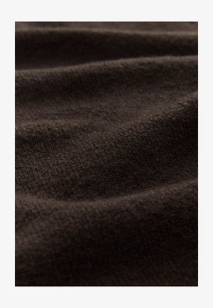 Ruskea teksturoidun kankaan pinta on pehmeä ja uritettu, jossa näkyy hienovaraisia ryppyjä ja vaihtelevia tummanruskean sävyjä ympäriinsä.