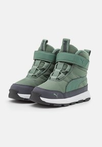 Scarpe sportive verdi con colletto imbottito, parte superiore in pelle sintetica e tessuto, strap in velcro, suola in gomma e dettagli grigi a contrasto.