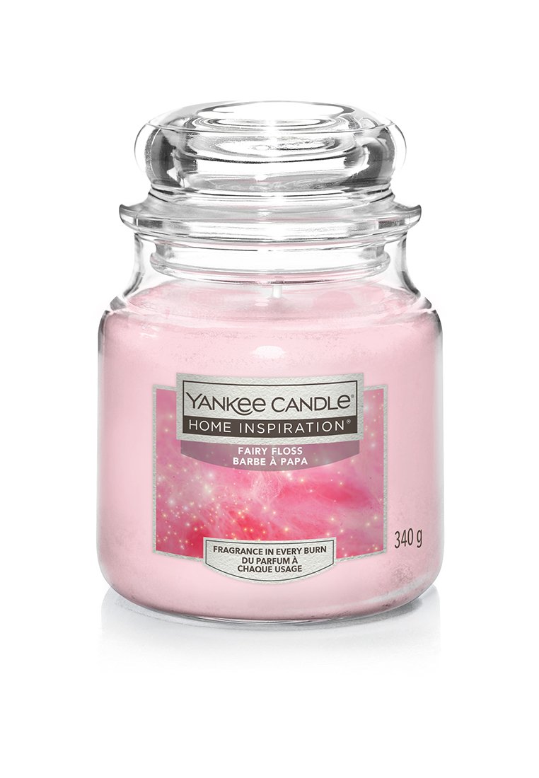 Bougie Yankee Candle dans un pot en verre transparent, cire rose, étiquetée "Fairy Floss". Présente un couvercle texturé et un design d'étiquette coloré et pastel.