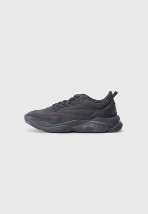 Black athletic shoes with a mesh and synthetic upper, featuring a rounded toe, textured sole, and prominent brand logo on the heel.