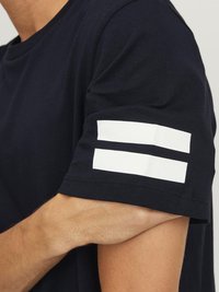 Camiseta de manga corta de color azul marino con dos rayas blancas horizontales en las mangas. Fabricada en suave algodón y con diseño de cuello redondo.