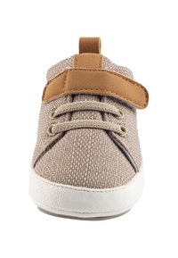 Beige fabric sneaker with textured canvas upper, tan faux leather strap, white rubber sole, and traditional lace-up design.