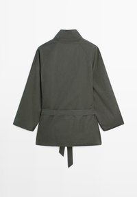 Donkergrijze lange mouwen jas met hoge kraag en vastzittende tailleband, weergegeven van achteren tegen een witte achtergrond.