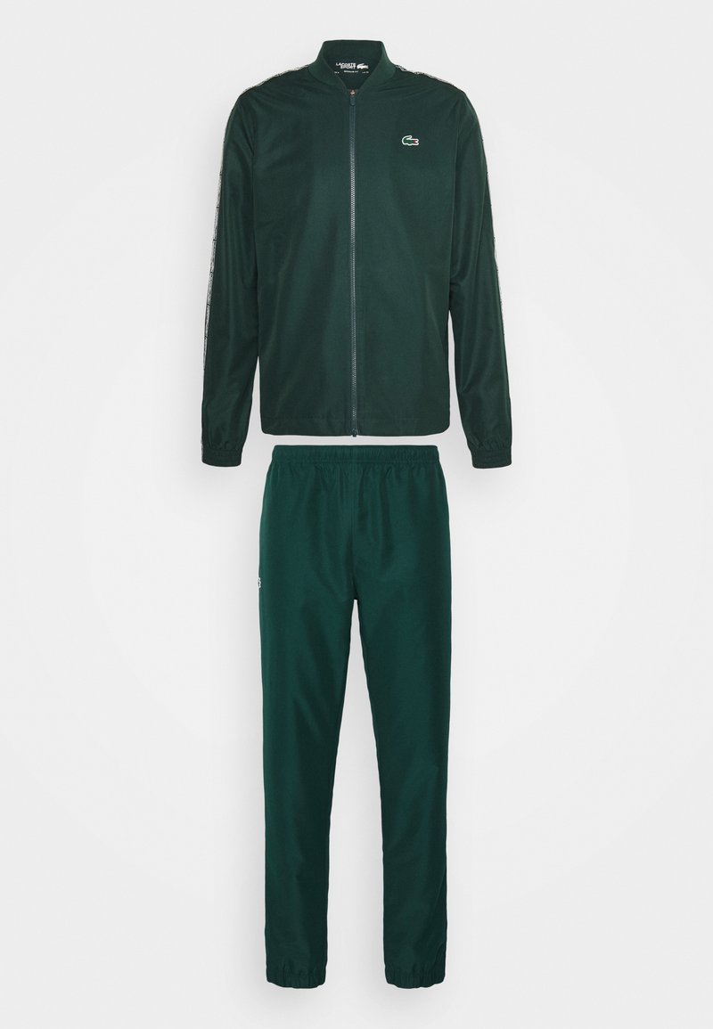 Chaqueta de chándal de color verde oscuro con cremallera completa y cinta de marca en las mangas, combinada con pantalones de chándal de cintura elástica a juego con puños en los tobillos.