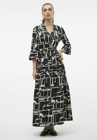 Abito maxi in bianco e nero con motivi geometrici, scollo a V, vita cinchata e gonna a strati, dotato di maniche a 3/4 e cintura con fiocco.