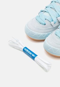 Ljust blå sportskor i mocka och mesh, med en texturerad sula, meshsnörning och en vit Adidas-märkt snörning.