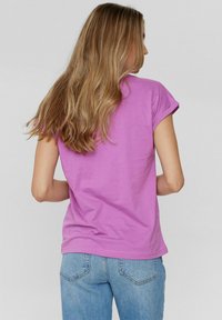 Paarse T-shirt met korte mouwen, gemaakt van zacht katoen, met een relaxte pasvorm en opgerolde mouwen, gecombineerd met een blauwe jeans.