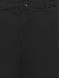 Črne hlače iz bližine, prikazujejo gumb, zanko za pas, šiv in teksturo blaga.