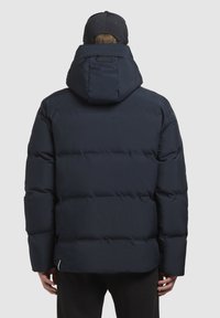 Marineblå pufferjakke med hætte, der har en quiltet tekstur, tykk polstring og snøre ved halsen, designet til varme.