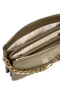 Borsa a tracolla in pelle verde oliva con tracolla in catena dorata, chiusura a zip e scomparti multipli foderati in tessuto chiaro.