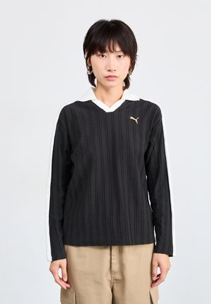 Black long-sleeve polo shirt with white collar and striped texture, featuring a gold logo and contrasting white side accents.