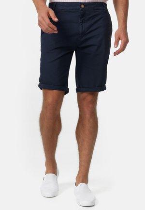Bermudas de algodón azul marino con puños doblados, bolsillos delanteros y cierre de botón. Diseño elegante con una textura suave y sin patrones visibles.