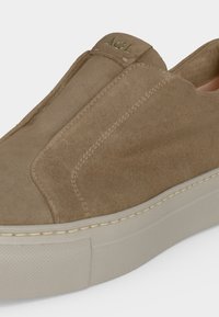 Baskets beige en daim à enfiler avec une semelle épaisse en caoutchouc blanc cassé et le logo AGL embossé sur la languette.