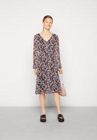 Vestido midi floral com mangas longas, decote em V, cintura franzida e fundo escuro. Acessórios incluem uma pequena bolsa rosa e sandálias de salto bloco pretas.