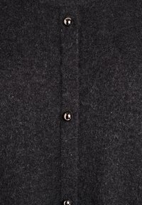 Tamsiai pilkas vilnonis kardiganas, pasižymintis švelnia tekstūra, mygtukų priekyje su blizgiais juodais mygtukais ir paprastu, klasikinio dizaino. 