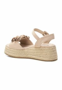 Sandalias de plataforma beige con suela de yute trenzado, que presentan un acento de tela con volantes en la parte delantera y una correa en el tobillo ajustable.