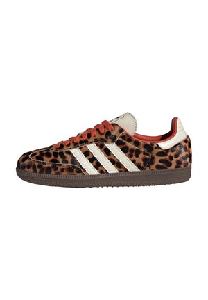 Lav sko med brun og sort leopardprint, hvide striber, røde snørebånd og en brun sål, vendt mod venstre på hvid baggrund.