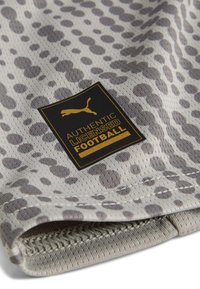 Sivi nogomet s teksturiranom površinom koja sadrži uzorak leopardove boje i crnu oznaku s natpisom "Autentični licencirani nogomet."