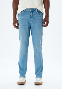 Jeans de mezclilla azul claro con corte recto. Presentan un cierre de botón y cremallera, cinco bolsillos y un ligero desgastado en los muslos.