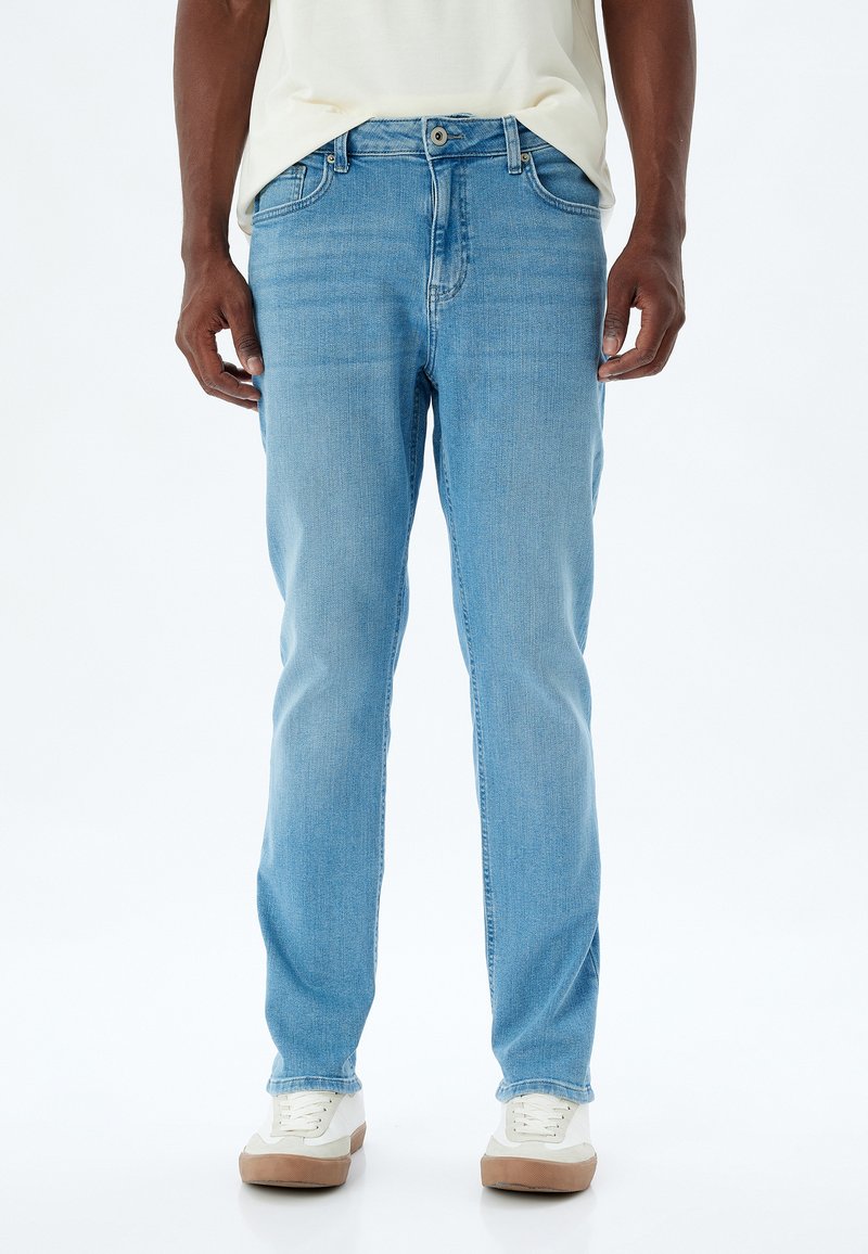 Jeans de mezclilla azul claro con corte recto. Presentan un cierre de botón y cremallera, cinco bolsillos y un ligero desgastado en los muslos.