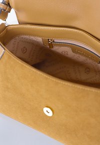 Mosterdgele handtas van suède met een gladde textuur. Het interieur heeft een ritsvak en heeft een merkvoering. De sluiting heeft een goudkleurige accent.