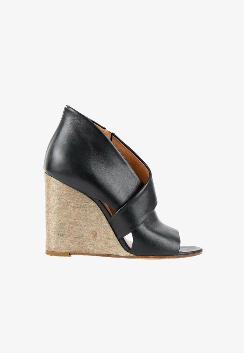 Chaussure compensée en cuir noir à bout ouvert avec un talon haut en liège et une large bride sur le pied, vue de côté.