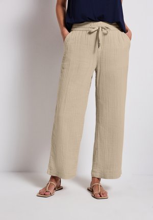 Pantaloni beige a gamba larga realizzati in tessuto testurizzato, con cintura elastica e cordino, dotati di tasche laterali e vestibilità comoda.