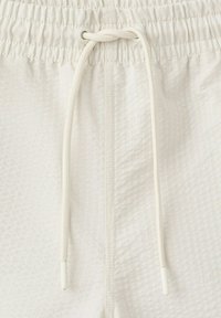 Shorts en tissu blanc texturé avec taille élastique et cordon à nouer au centre avant.