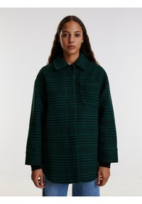 Groen en zwart geruite overhemdjack met lange mouwen, een knoopsluiting bij de kraag en een voorzak. Gemaakt van textuurstof.