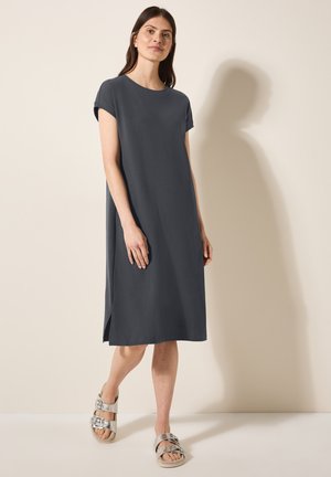 Short-sleeve, knee-length dress in dark gray fabric with a relaxed fit, featuring side slits and paired with metallic sandals.