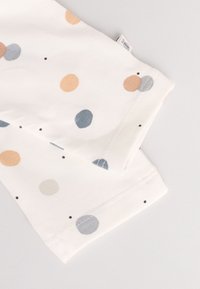 Tissu en coton blanc avec des pois multicolores en pêche, bleu, gris et noir. Présente des bords cousus et une petite étiquette.