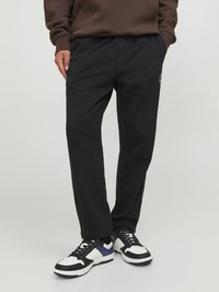 Pantalones de chándal negros de algodón con cinturilla elástica y cordón. Cuenta con bolsillos laterales y un pequeño detalle de logo.