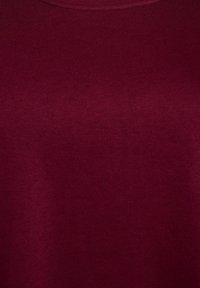 Bordo krūšdaļa t-krekls, izgatavots no mīkstas auduma. Gluda tekstūra ar minimālu šuvju detaļu, piemērots ikdienas valkāšanai.