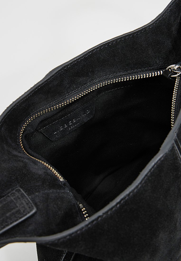 Bolso de ante negro abierto para mostrar el interior forrado de tela negra y un bolsillo interior con cremallera visible en color plateado.