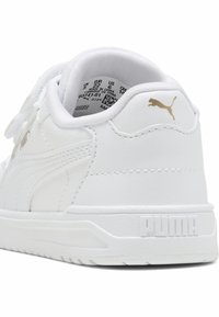 Sneaker in pelle bianca con una texture liscia, caratterizzato da un logo Puma dorato, un colletto imbottito e una suola in gomma con dettagli testurizzati.