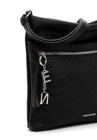 Black leather handbag with a zippered closure, textured surface, and a silver charm featuring letters. Accented with a detachable strap.