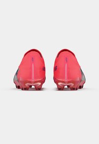 Raudoni futbolo batai su moderniu dizainu, turintys tekstūruotą viršutinę dalį ir skaidrius padas, užtikrinantys sukibimą ir stabilumą.