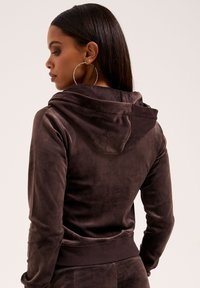 Brown velours hoodie met een trekkoord kap, geribde zoom en lange mouwen. Gladde textuur met een getailleerde uitstraling.