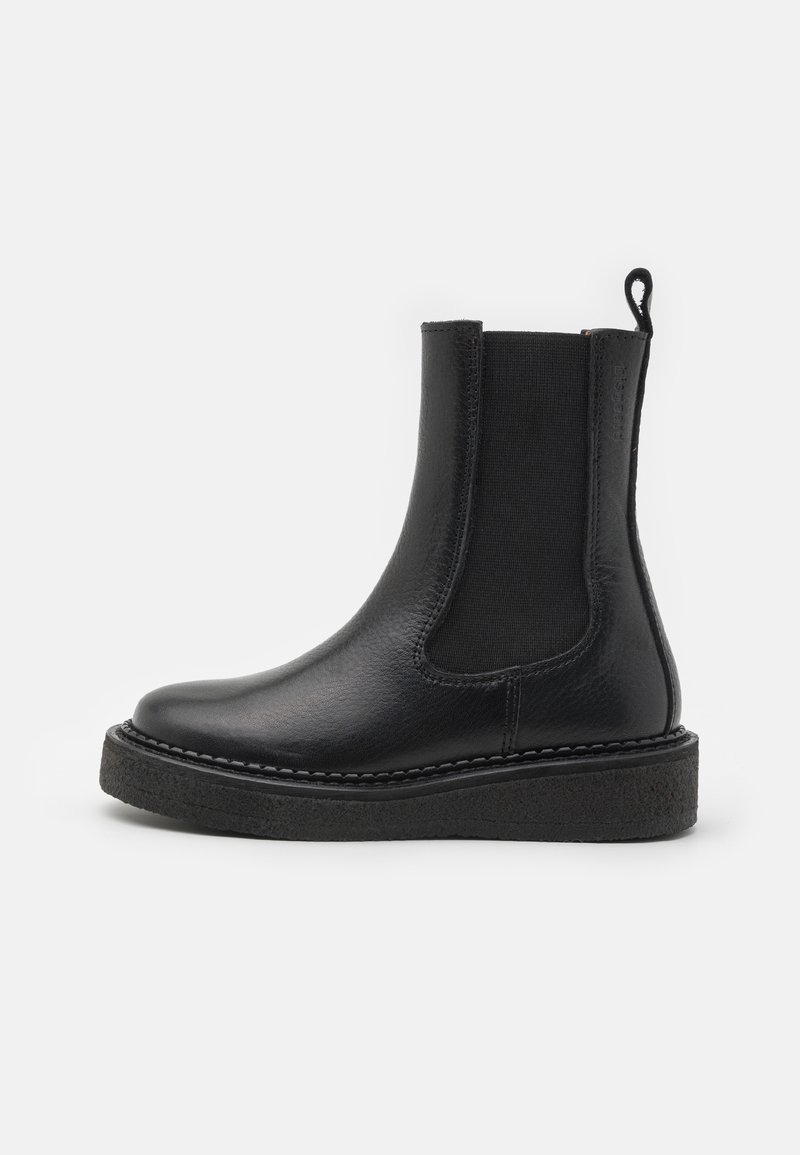 Botte Chelsea en cuir noir avec panneau latéral élastique, languette de traction à l'arrière et semelle épaisse texturée, vue de profil sur fond blanc.