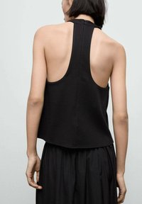 Top senza maniche nero con scollatura alta e schiena scoperta, realizzato in tessuto testurizzato, dotato di una zip centrale sul retro e orlo arrotondato.