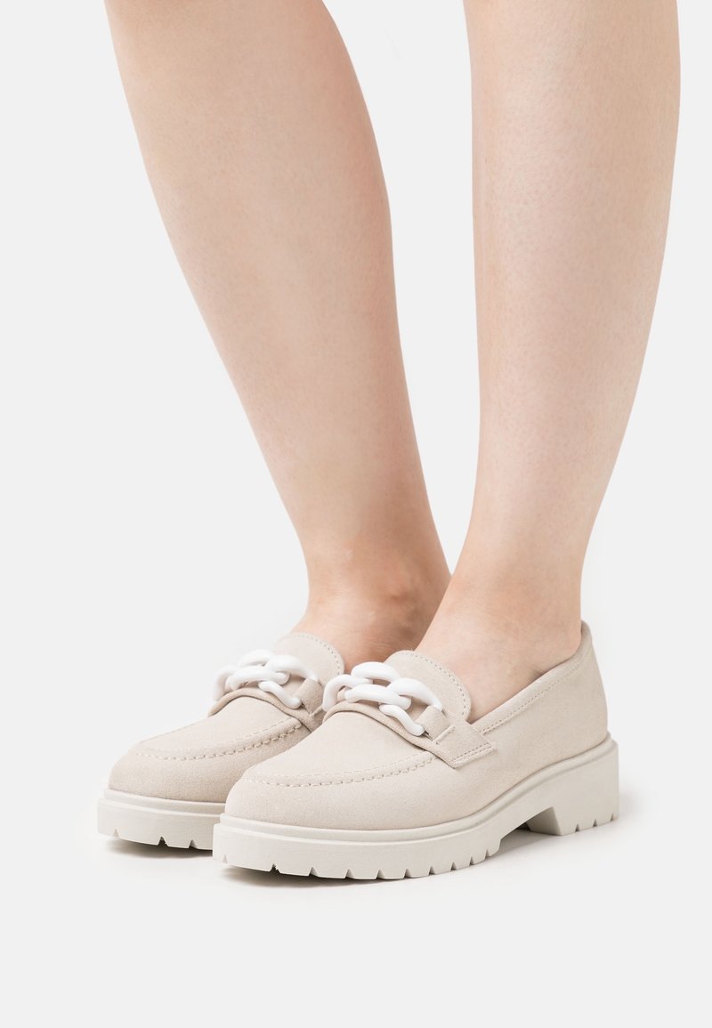 Mocassini in suede beige con lacci bianchi, dotati di una suola bianca spessa e dettagli di cucitura, progettati per un uso casual.