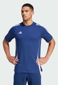 Blue athletic t-shirt made of breathable fabric, featuring white side stripes and an Adidas logo on the left chest. Short sleeves, relaxed fit.