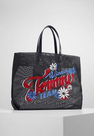 Musta verkkokangaskassi mustilla kahvoilla, koristeltu punaisella, sinisellä ja valkoisella kirjotulla tekstillä "Winning Tommy Team" ja kukkakuvioilla.