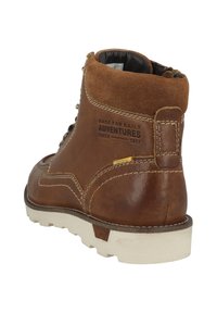 Bota de cuero marrón con acentos de ante, suela de goma blanca y detalles cosidos. Incluye un asa de tirón y texto en relieve en el talón.
